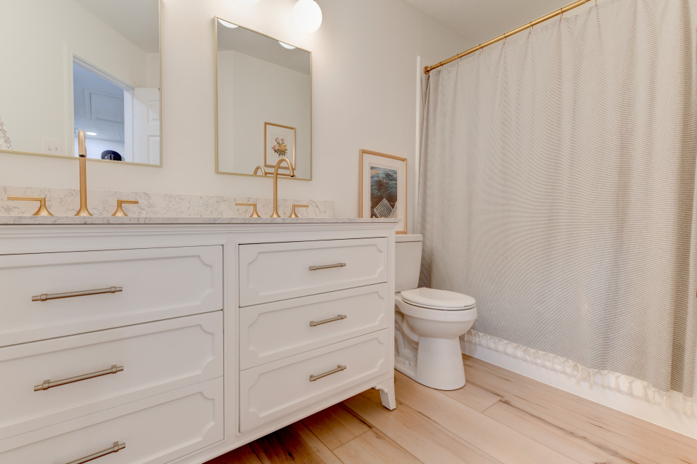 Klassisk inredning av ett mycket stort vit vitt en-suite badrum, med vita skåp, en toalettstol med hel cisternkåpa, beige väggar, vinylgolv, ett nedsänkt handfat, marmorbänkskiva och beiget golv