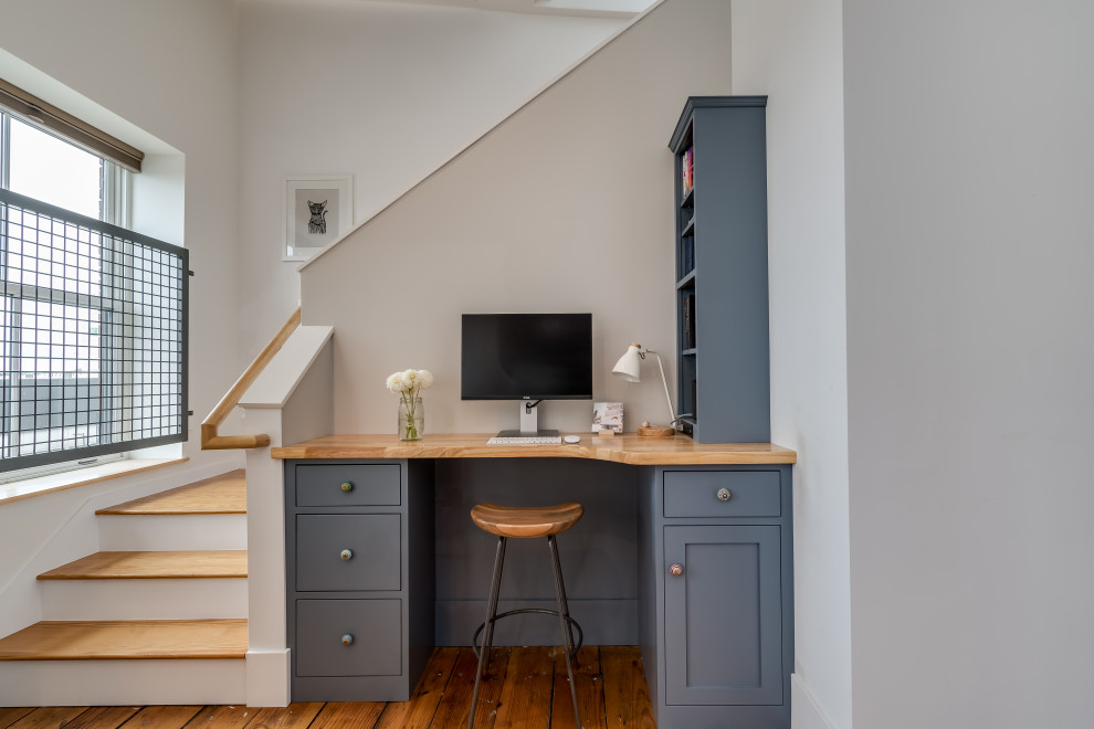 Example of a small transitional built-in desk medium tone wood floor study room design in Portland Maine with white walls