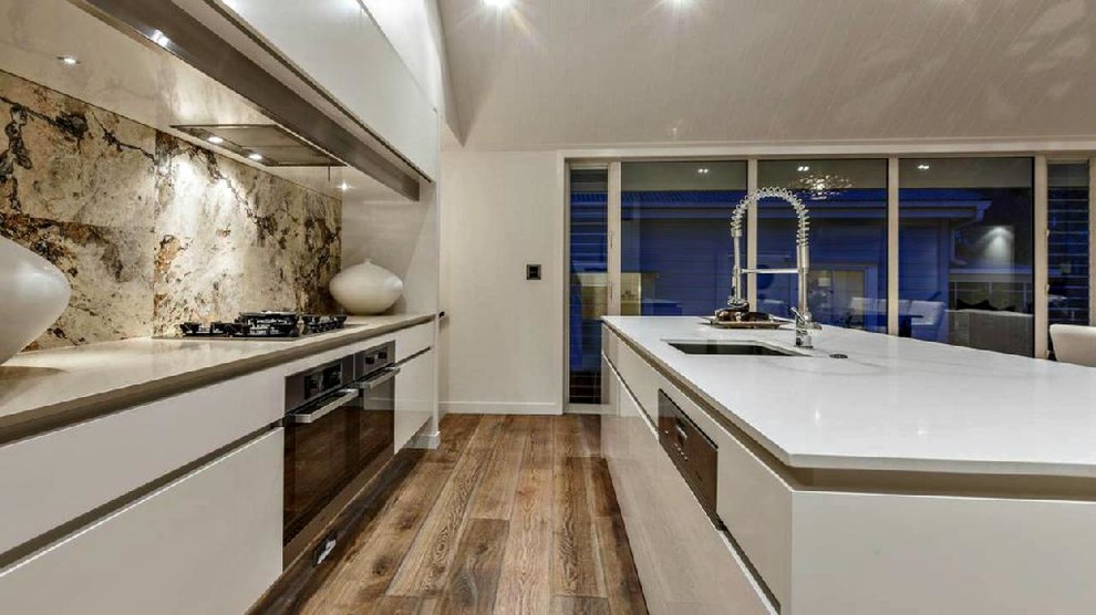 Inspiration for a mid-sized contemporary single-wall open plan kitchen in New York with a single-bowl sink, flat-panel cabinets, white cabinets, multi-coloured splashback, stainless steel appliances, light hardwood floors and with island.