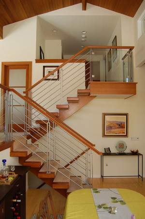 Photo of a mid-sized transitional carpeted l-shaped staircase in Seattle with open risers and wood railing.