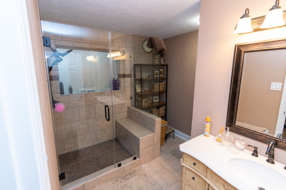Exemple d'une salle de bain principale chic de taille moyenne avec un placard en trompe-l'oeil, des portes de placard beiges, une douche d'angle, un carrelage marron, des carreaux de céramique, une cabine de douche à porte battante, meuble simple vasque et meuble-lavabo sur pied.