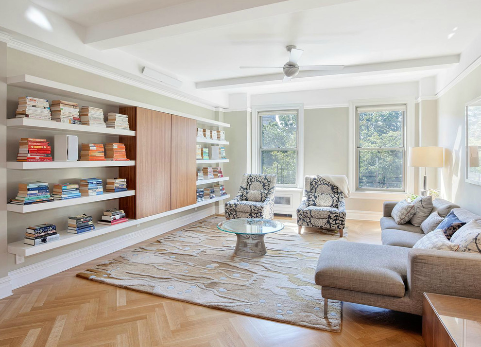 This is an example of a contemporary family room in New York with a library, grey walls and medium hardwood floors.