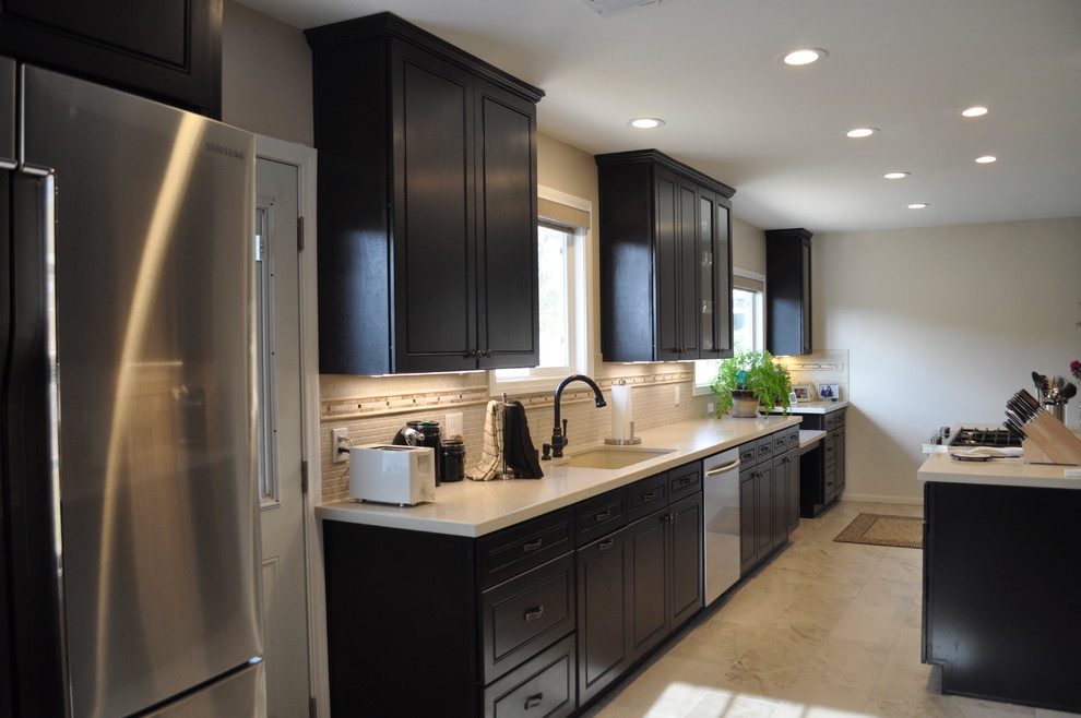 Example of a large galley marble floor and white floor enclosed kitchen design in Orange County with an undermount sink, raised-panel cabinets, dark wood cabinets, solid surface countertops, white backsplash, mosaic tile backsplash, stainless steel appliances and an island