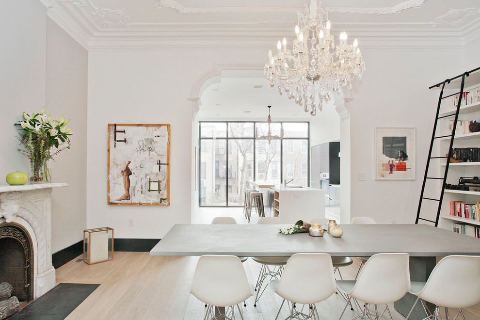 Large scandinavian separate dining room in New York with white walls, light hardwood floors, a standard fireplace and a stone fireplace surround.