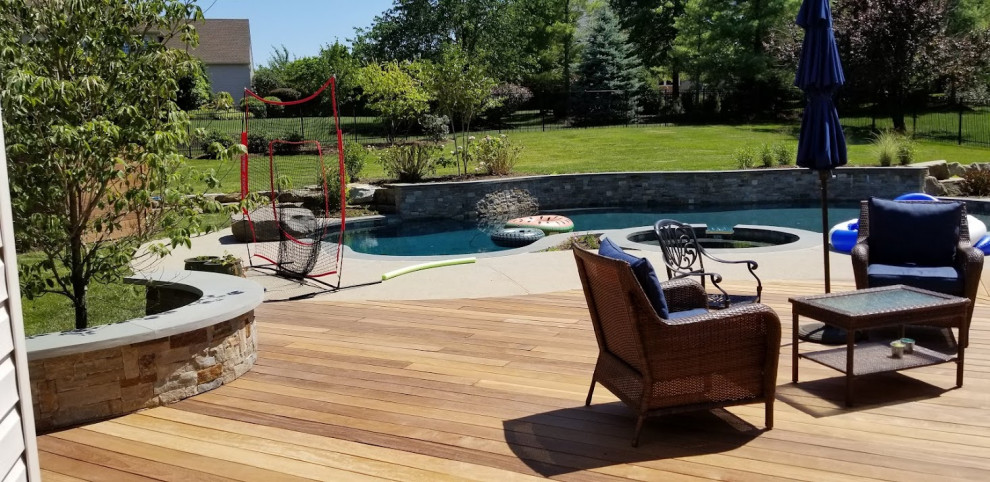 Foto di una grande piscina naturale design a "C" dietro casa con paesaggistica bordo piscina e pedane