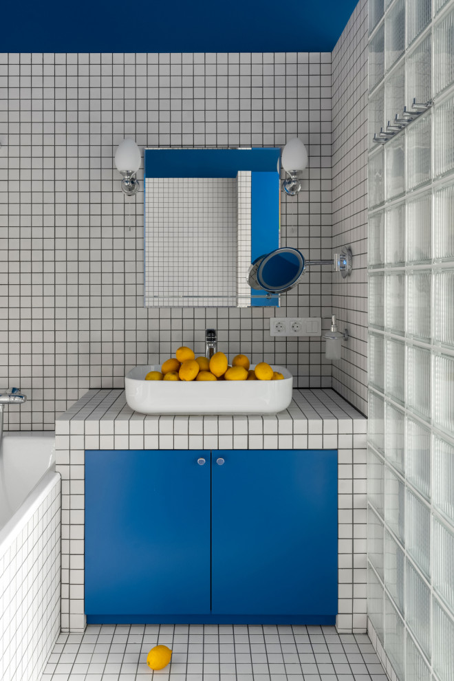 Пример оригинального дизайна: большая ванная комната в современном стиле с синими фасадами, ванной в нише, душем в нише, белой плиткой, плиткой мозаикой, белыми стенами, полом из мозаичной плитки, душевой кабиной, столешницей из плитки, белым полом, белой столешницей, тумбой под одну раковину и встроенной тумбой