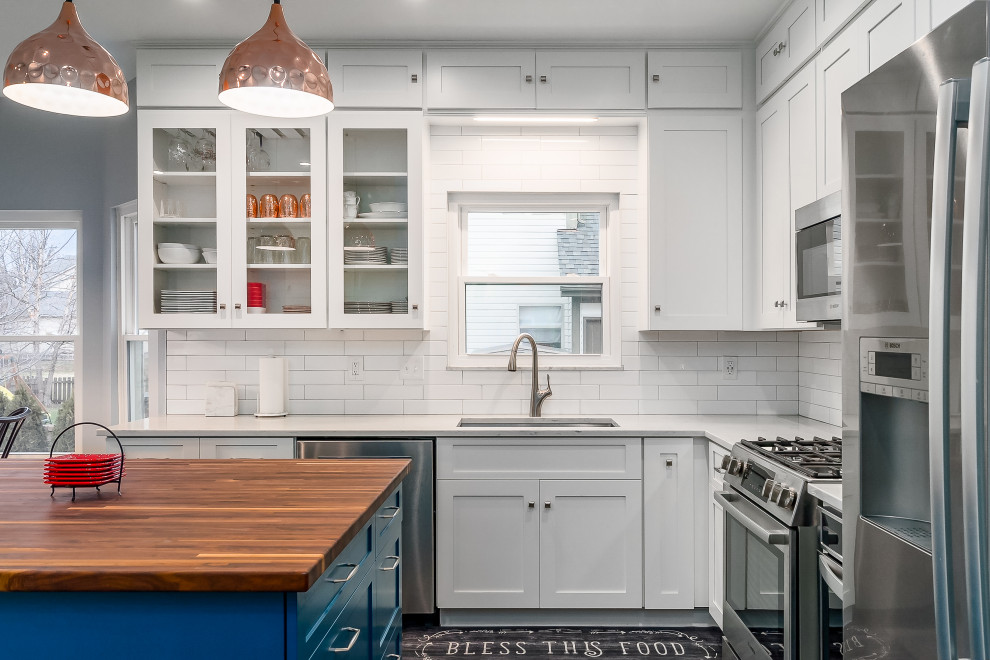 Design ideas for a mid-sized transitional l-shaped eat-in kitchen in Columbus with shaker cabinets, quartz benchtops, white splashback, subway tile splashback and with island.