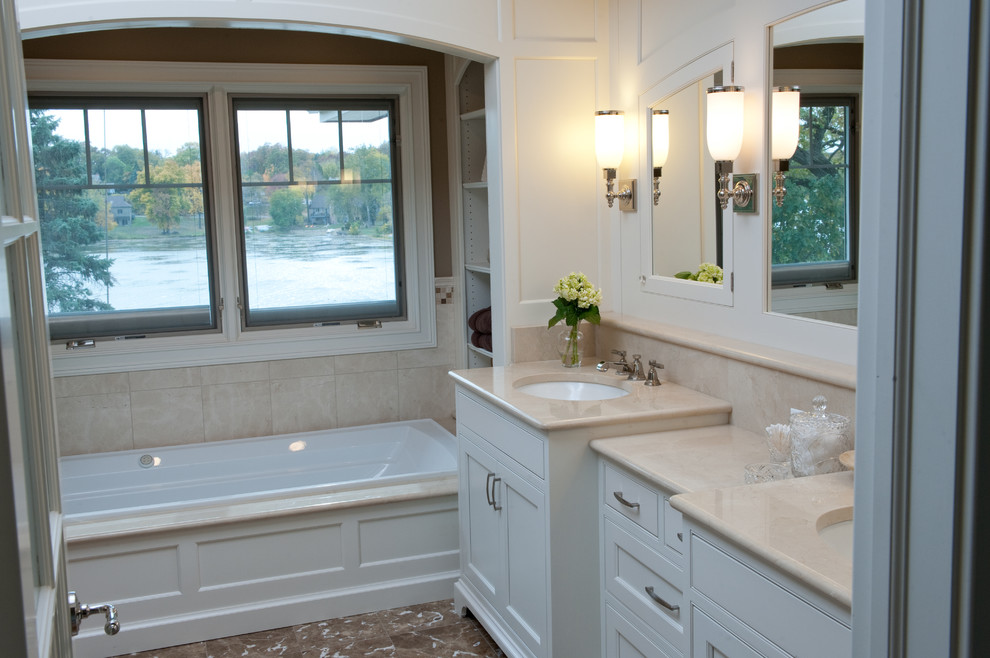 This is an example of a large traditional master bathroom in Chicago with beaded inset cabinets, white cabinets, a drop-in tub, an open shower, a two-piece toilet, beige tile, porcelain tile, brown walls, marble floors, an undermount sink, marble benchtops, brown floor, an open shower and beige benchtops.