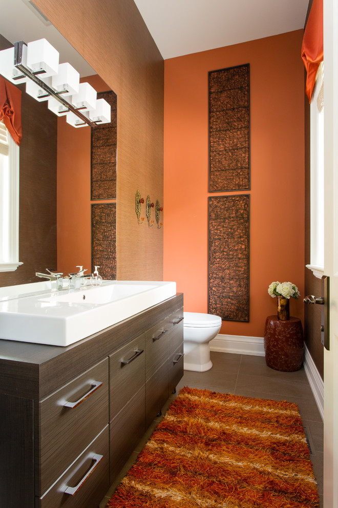 Mid-sized transitional powder room in Toronto with flat-panel cabinets, dark wood cabinets, a vessel sink, brown tile, ceramic tile, multi-coloured walls, ceramic floors and brown floor.