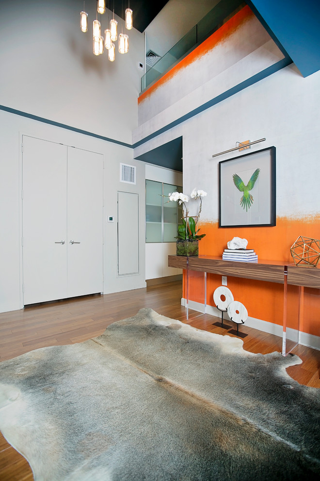 Entryway - mid-sized contemporary medium tone wood floor entryway idea in New York with orange walls and a gray front door