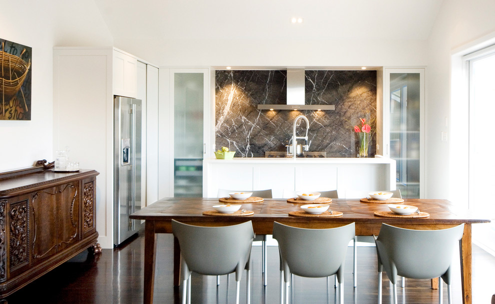Inspiration for a small contemporary l-shaped eat-in kitchen in Auckland with stainless steel appliances, flat-panel cabinets, white cabinets, quartz benchtops, brown splashback, dark hardwood floors and with island.