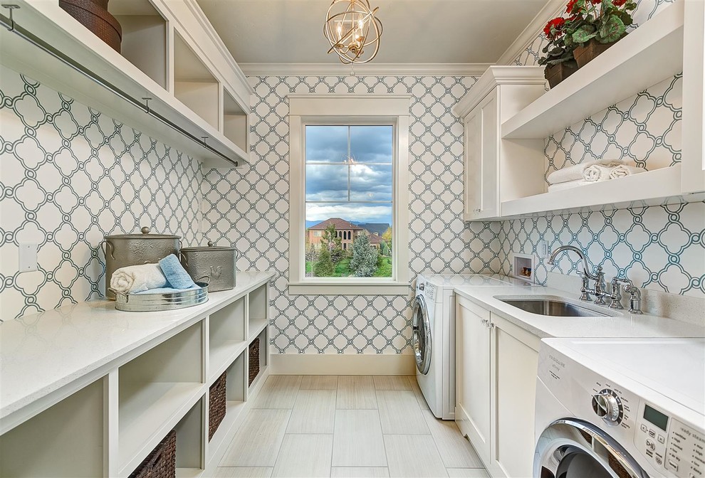 This is an example of a large transitional galley dedicated laundry room in Boise with an undermount sink, shaker cabinets, white cabinets, multi-coloured walls, quartz benchtops, porcelain floors, a side-by-side washer and dryer, grey floor and white benchtop.