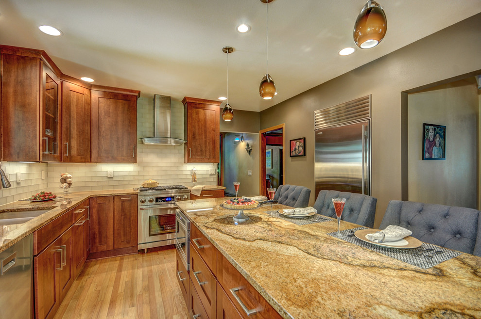 Large transitional l-shaped light wood floor enclosed kitchen photo in Milwaukee with an undermount sink, shaker cabinets, medium tone wood cabinets, granite countertops, beige backsplash, glass tile backsplash, stainless steel appliances and an island