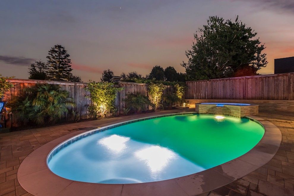 Mid-sized transitional backyard round lap pool in Orange County with a hot tub and natural stone pavers.