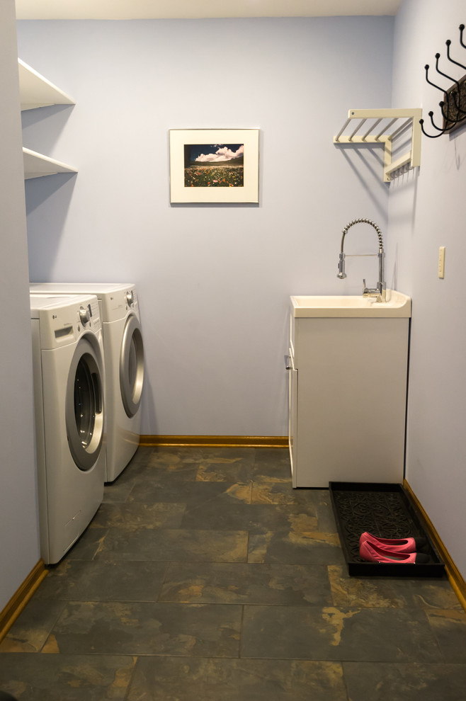 Example of a large transitional galley porcelain tile dedicated laundry room design with an utility sink, open cabinets, white cabinets, solid surface countertops, blue walls and a side-by-side washer/dryer