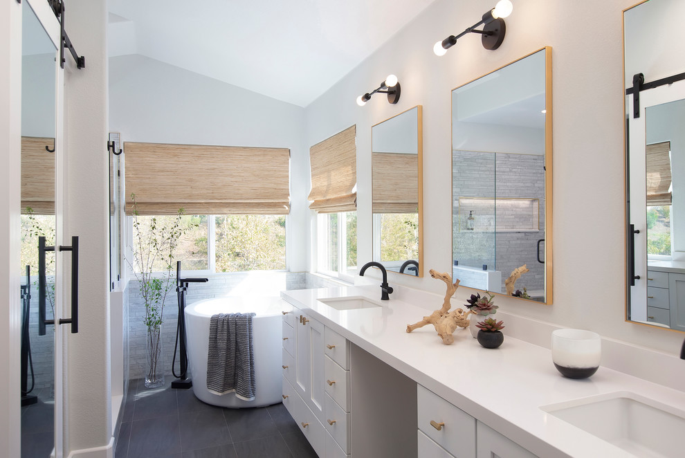 Photo of a transitional master bathroom in San Diego with shaker cabinets, white cabinets, a freestanding tub, an alcove shower, gray tile, white walls, an undermount sink, grey floor, white benchtops, stone tile, porcelain floors, engineered quartz benchtops and a sliding shower screen.