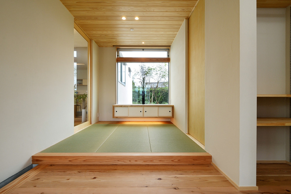 Стильный дизайн: большая узкая прихожая с белыми стенами, татами, раздвижной входной дверью, входной дверью из дерева среднего тона, зеленым полом, деревянным потолком и обоями на стенах - последний тренд