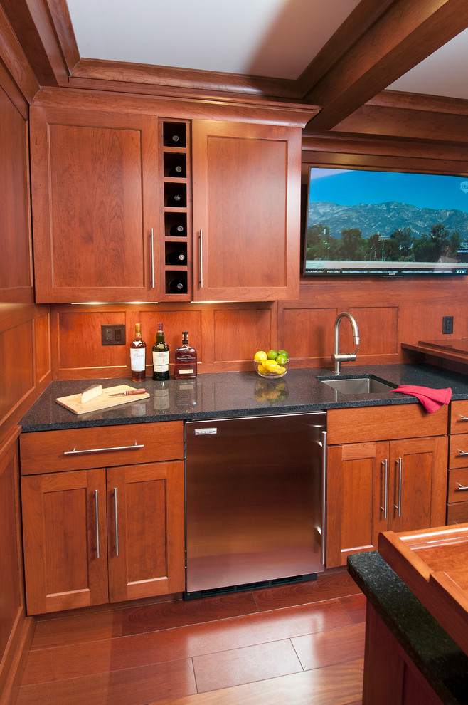 Small traditional u-shaped seated home bar in Other with an undermount sink, shaker cabinets, medium wood cabinets, granite benchtops and medium hardwood floors.