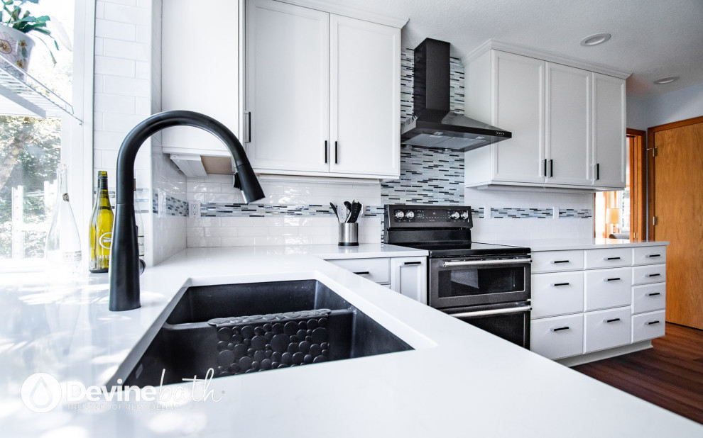 Open concept kitchen - large transitional l-shaped medium tone wood floor open concept kitchen idea in Portland with an undermount sink, recessed-panel cabinets, white cabinets, quartz countertops, white backsplash, glass tile backsplash, stainless steel appliances, an island and white countertops