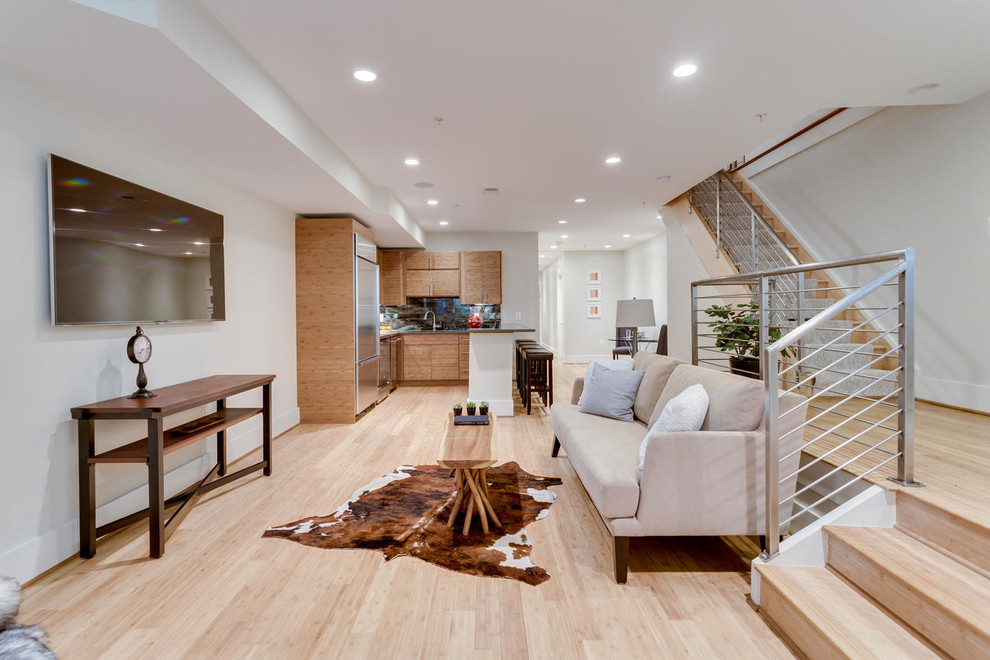 This is an example of a mid-sized modern walk-out basement in DC Metro with grey walls, bamboo floors, no fireplace and beige floor.