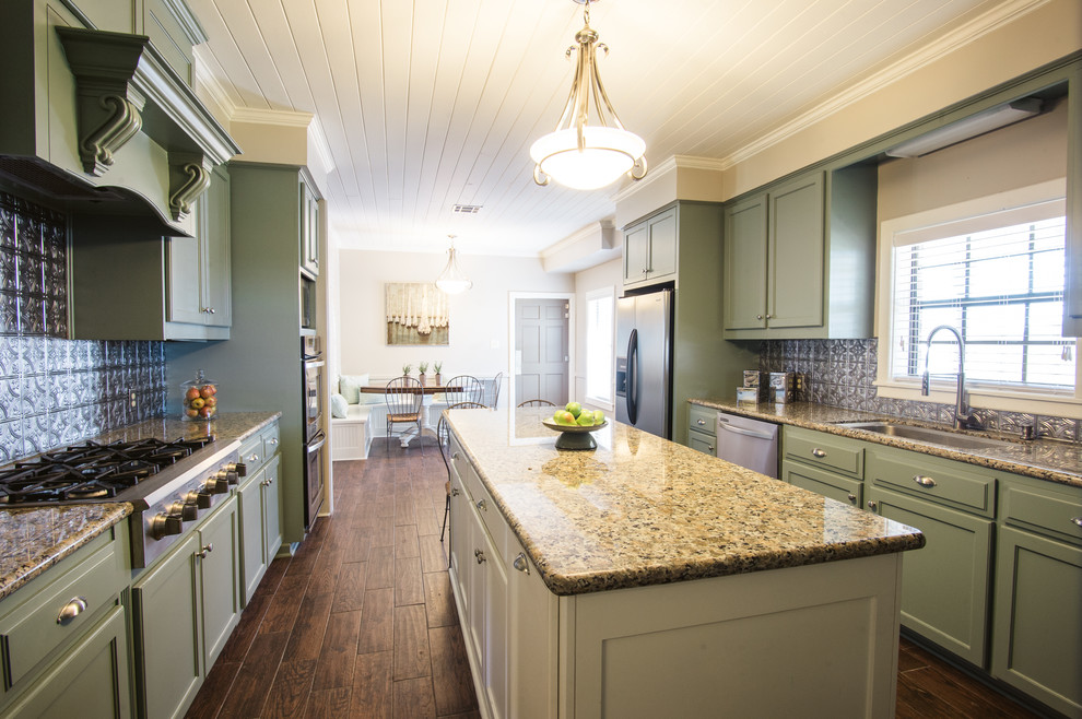 This is an example of a mid-sized country galley eat-in kitchen in New Orleans with a drop-in sink, shaker cabinets, green cabinets, granite benchtops, metallic splashback, metal splashback, stainless steel appliances, medium hardwood floors and with island.