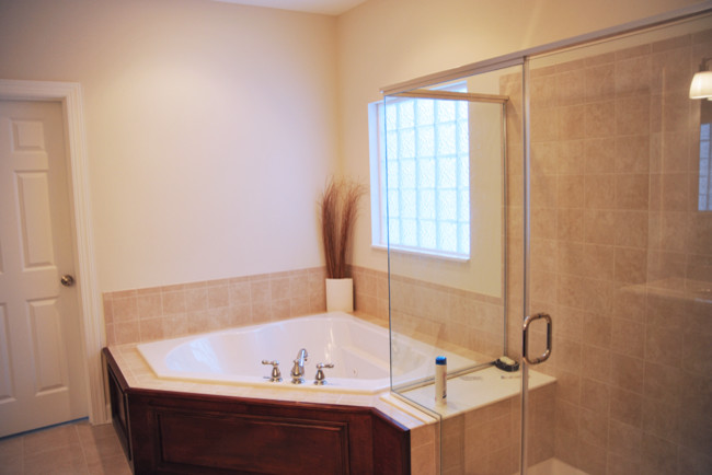 Photo of a mid-sized contemporary master bathroom in Columbus with flat-panel cabinets, medium wood cabinets, a corner tub, a shower/bathtub combo, beige tile, porcelain tile, white walls, porcelain floors and solid surface benchtops.