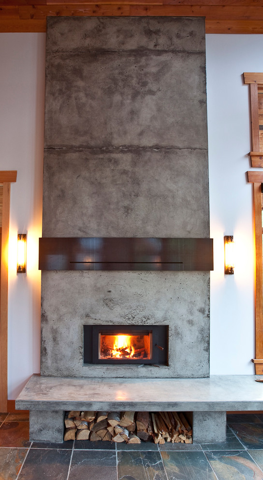 This is an example of a country open concept living room in Calgary with slate floors and a concrete fireplace surround.