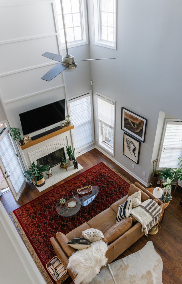 Kleines Eklektisches Wohnzimmer im Loft-Stil mit weißer Wandfarbe, braunem Holzboden, Kamin, Kaminumrandung aus Backstein, TV-Wand, braunem Boden und Wandpaneelen in Atlanta