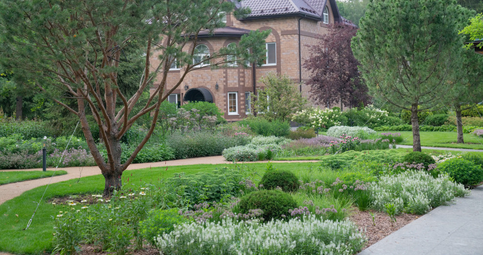 На фото: большой летний участок и сад на заднем дворе в стиле кантри с клумбами, полуденной тенью, покрытием из каменной брусчатки и с металлическим забором