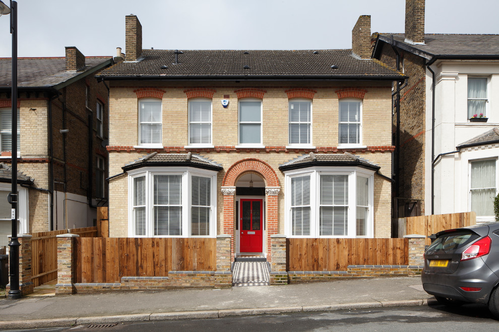 Large traditional brick beige house exterior in London with four or more storeys, a gable roof and a tile roof.