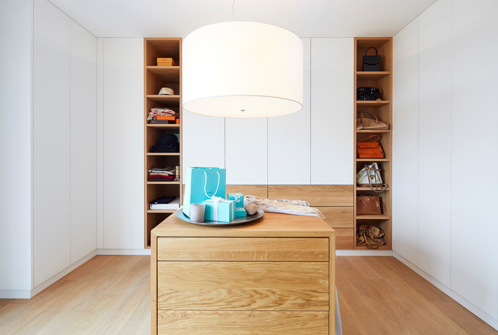 Inspiration for a mid-sized contemporary women's dressing room with flat-panel cabinets, white cabinets, medium hardwood floors and brown floor.