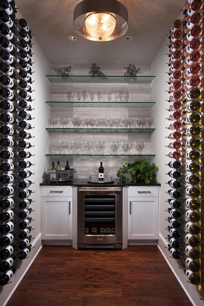 Photo of a mediterranean wine cellar in Other with dark hardwood floors and display racks.