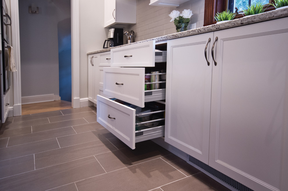 Example of a mid-sized transitional galley ceramic tile eat-in kitchen design in Montreal with an undermount sink, shaker cabinets, white cabinets, granite countertops, beige backsplash, subway tile backsplash, stainless steel appliances and an island