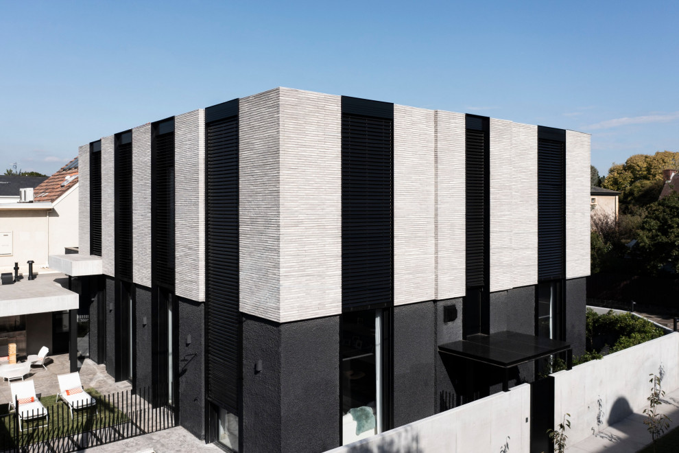 Cette image montre une grande façade de maison grise minimaliste en brique à un étage.
