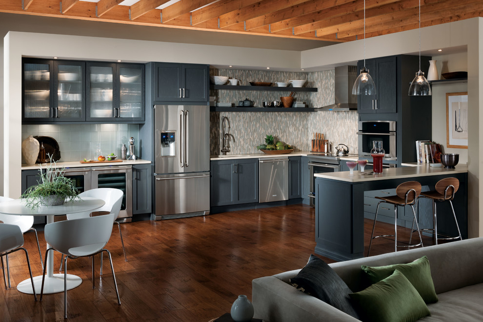 Inspiration for a large traditional u-shaped eat-in kitchen in New York with a double-bowl sink, shaker cabinets, blue cabinets, solid surface benchtops, grey splashback, matchstick tile splashback, stainless steel appliances, dark hardwood floors, a peninsula and brown floor.