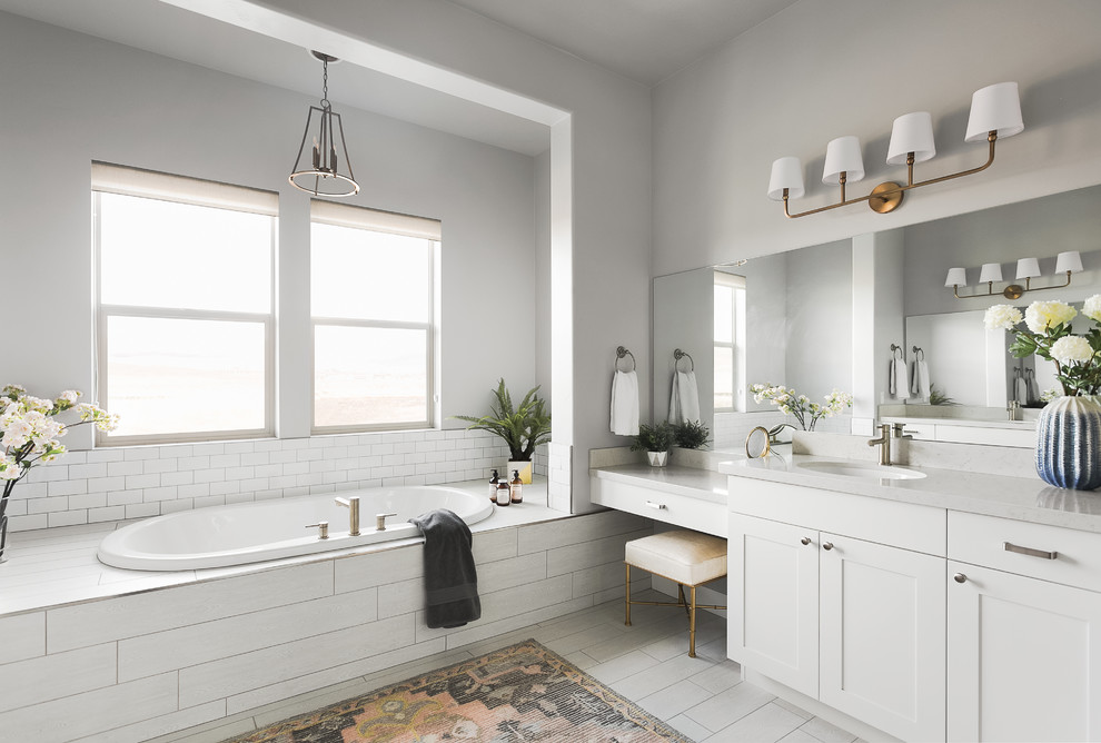 Inspiration for a transitional bathroom in Salt Lake City with shaker cabinets, white cabinets, a drop-in tub, white tile, subway tile, grey walls, an undermount sink, grey floor and white benchtops.