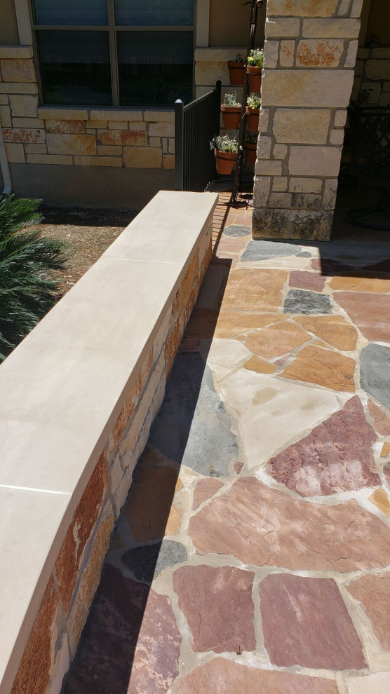 Photo of an expansive country backyard patio in Austin with natural stone pavers.