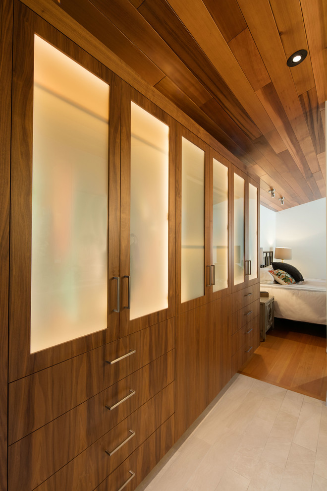 Inspiration for a large contemporary gender-neutral walk-in wardrobe in San Luis Obispo with glass-front cabinets, medium wood cabinets, ceramic floors and beige floor.