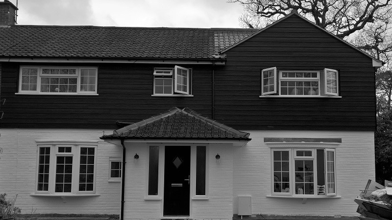 Photo of a medium sized and white classic two floor semi-detached house in Surrey with concrete fibreboard cladding, a hip roof and a tiled roof.
