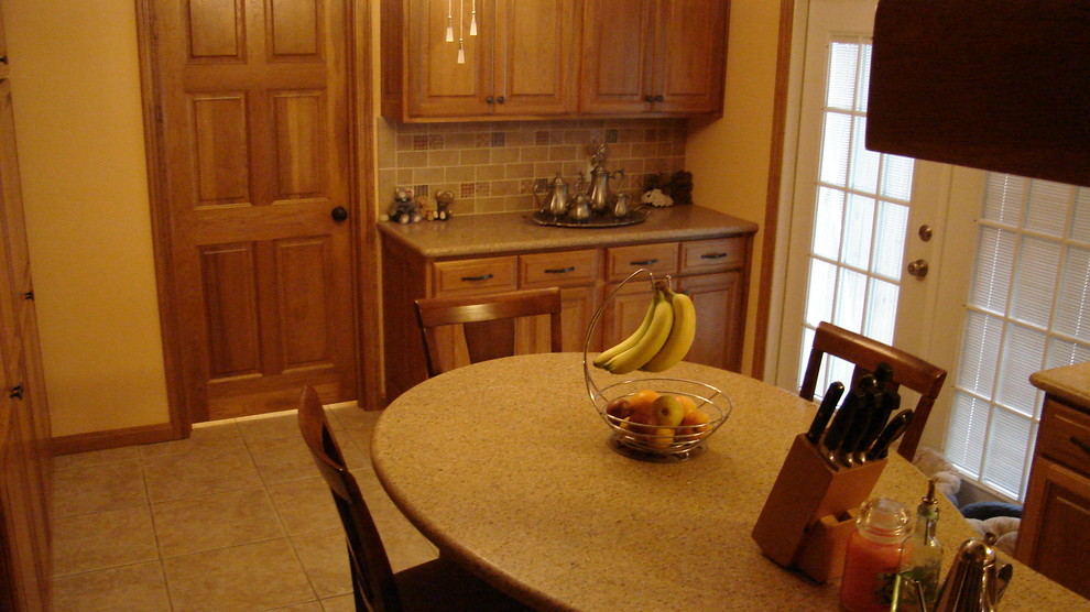 Mid-sized transitional l-shaped ceramic tile eat-in kitchen photo in Houston with a double-bowl sink, raised-panel cabinets, light wood cabinets, solid surface countertops, multicolored backsplash, subway tile backsplash, stainless steel appliances and an island