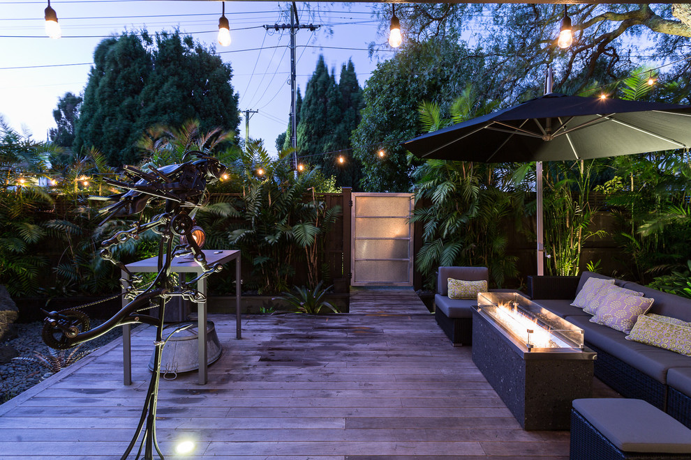 Inspiration for a mid-sized industrial courtyard patio in Auckland with a fire feature, decking and no cover.