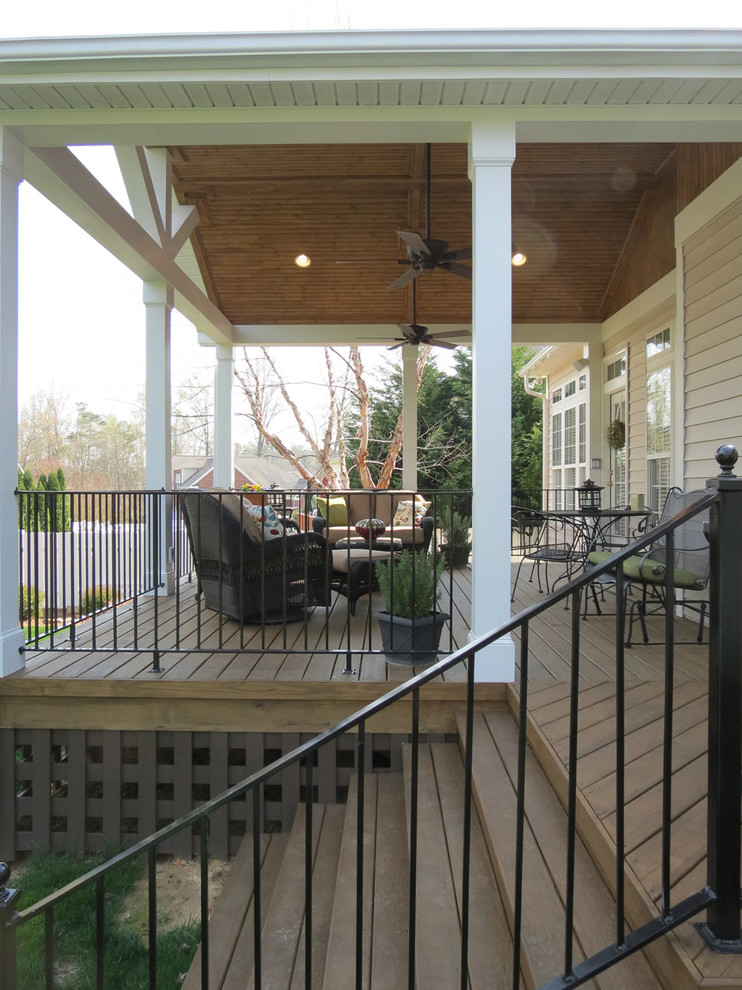 This is an example of a mid-sized contemporary backyard deck in Charlotte with a roof extension.