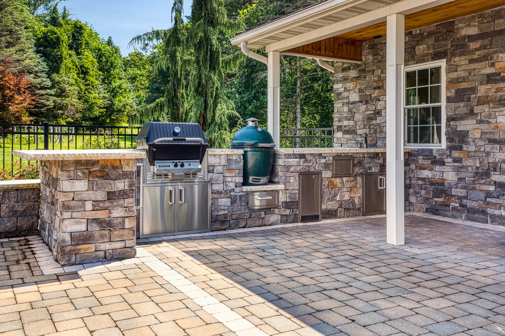 This is an example of a large traditional backyard custom-shaped pool in Philadelphia with a pool house and concrete pavers.