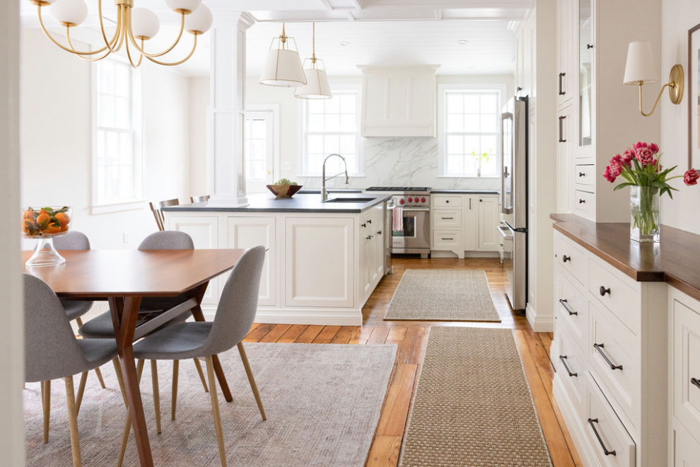 Inspiration för ett mellanstort vintage grå grått kök, med en undermonterad diskho, luckor med profilerade fronter, vita skåp, granitbänkskiva, vitt stänkskydd, stänkskydd i sten, rostfria vitvaror, mellanmörkt trägolv, en köksö och brunt golv