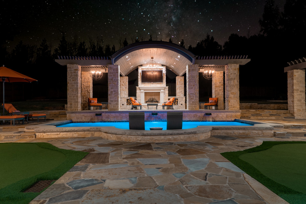 Large backyard patio in Dallas with with fireplace, natural stone pavers and a gazebo/cabana.