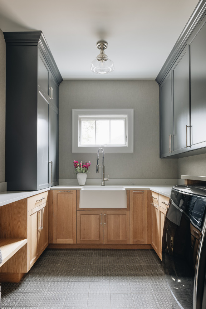 Inspiration for a large classic u-shaped separated utility room in Chicago with light wood cabinets, white worktops, a belfast sink, grey walls, a side by side washer and dryer and grey floors.