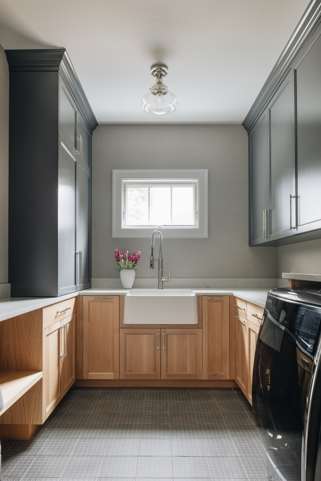 ASC Margaritaville - Example of a large transitional u-shaped gray floor dedicated laundry room design in Chicago with light wood cabinets, white countertops, a farmhouse sink, gray walls and a side-by-side washer/dryer