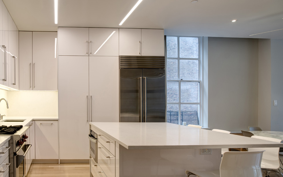 Inspiration for a mid-sized contemporary l-shaped kitchen in New York with an undermount sink, flat-panel cabinets, white cabinets, quartzite benchtops, beige splashback, stainless steel appliances and with island.