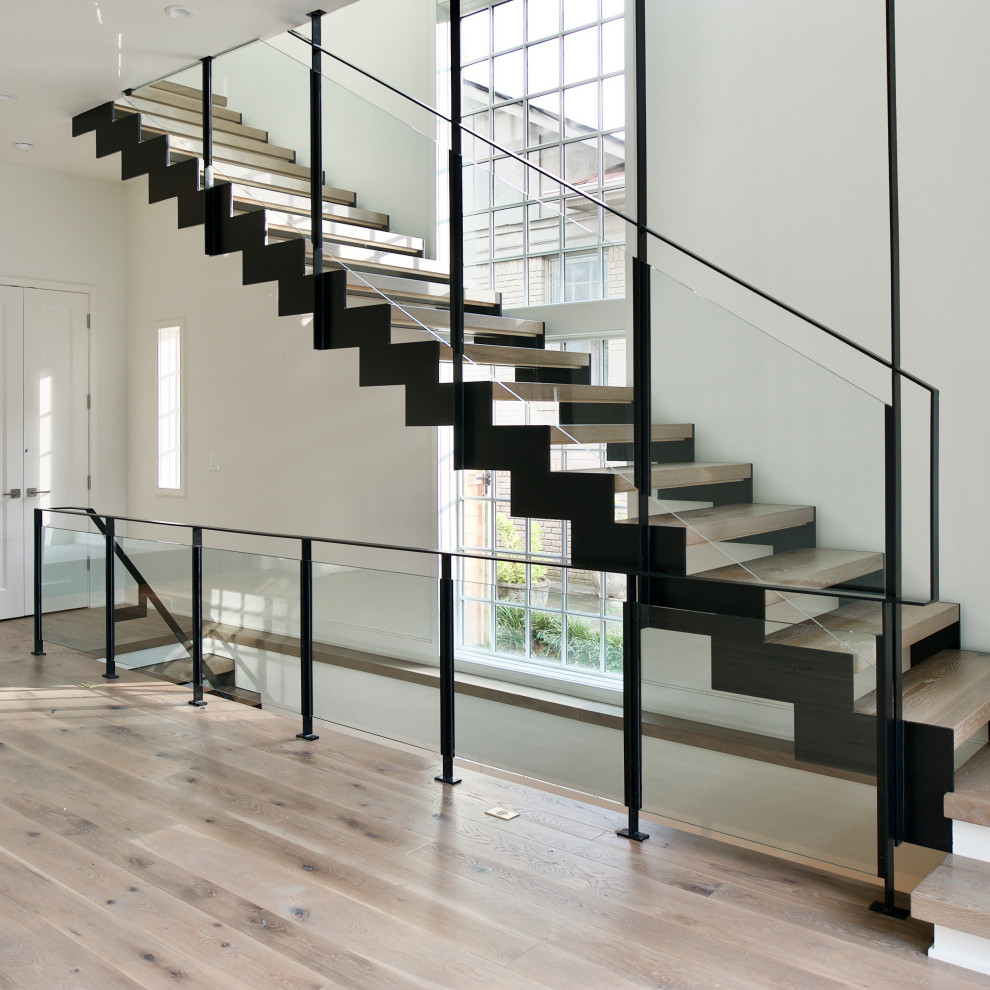 This is an example of a mid-sized industrial wood straight staircase in Atlanta with open risers and glass railing.