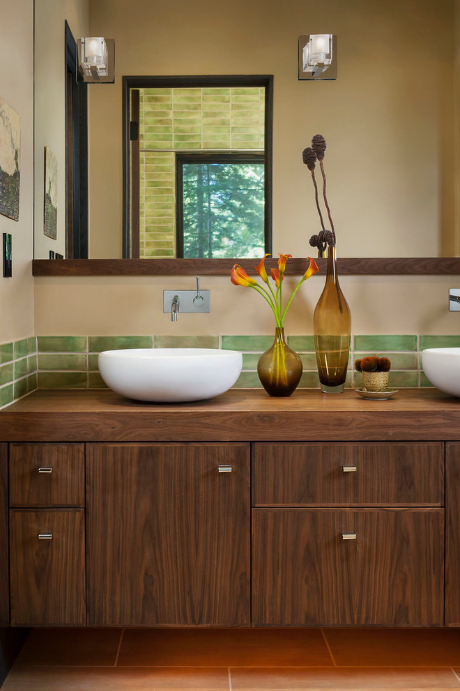 Mid-sized country bathroom in Other with a vessel sink, medium wood cabinets, wood benchtops, green tile, ceramic tile, beige walls and ceramic floors.